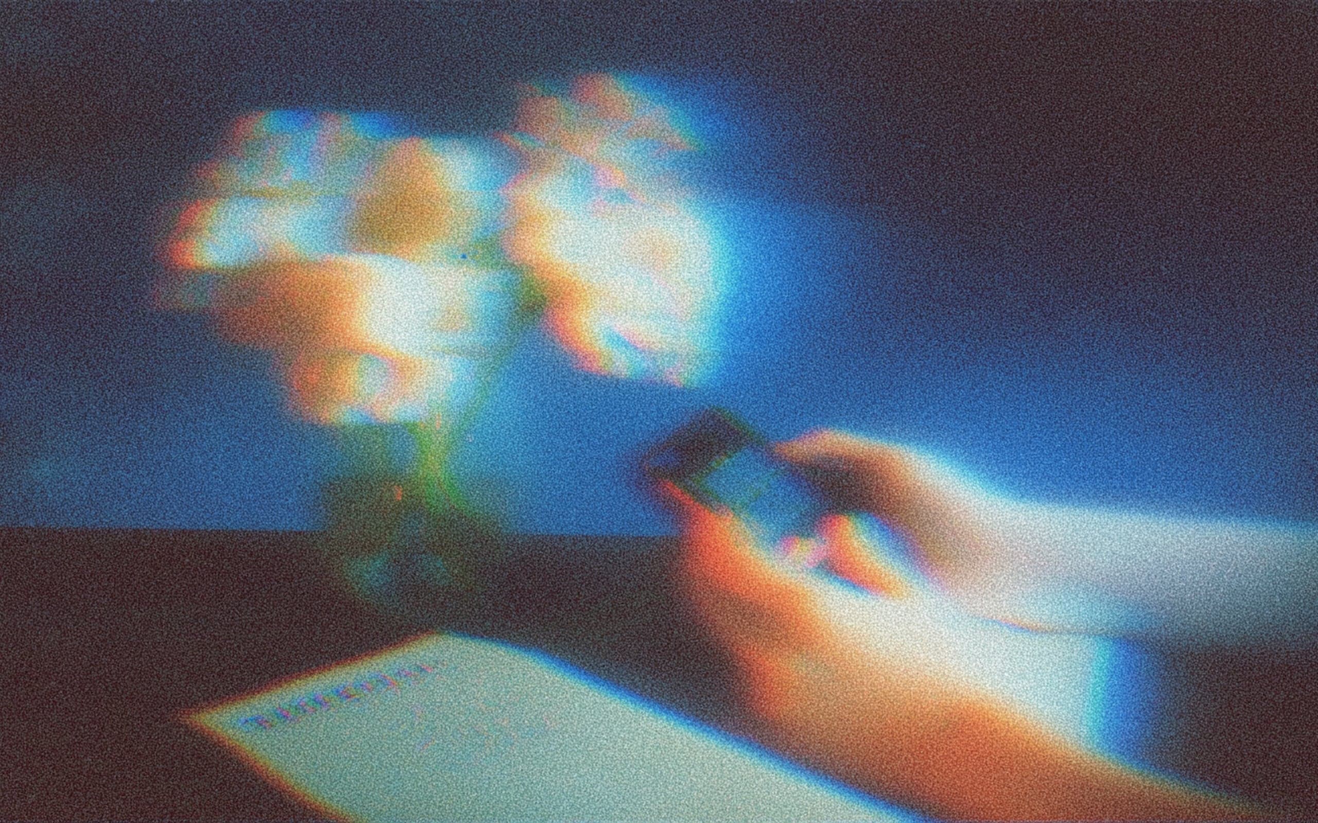 A hand holding a glowing phone in a dim room